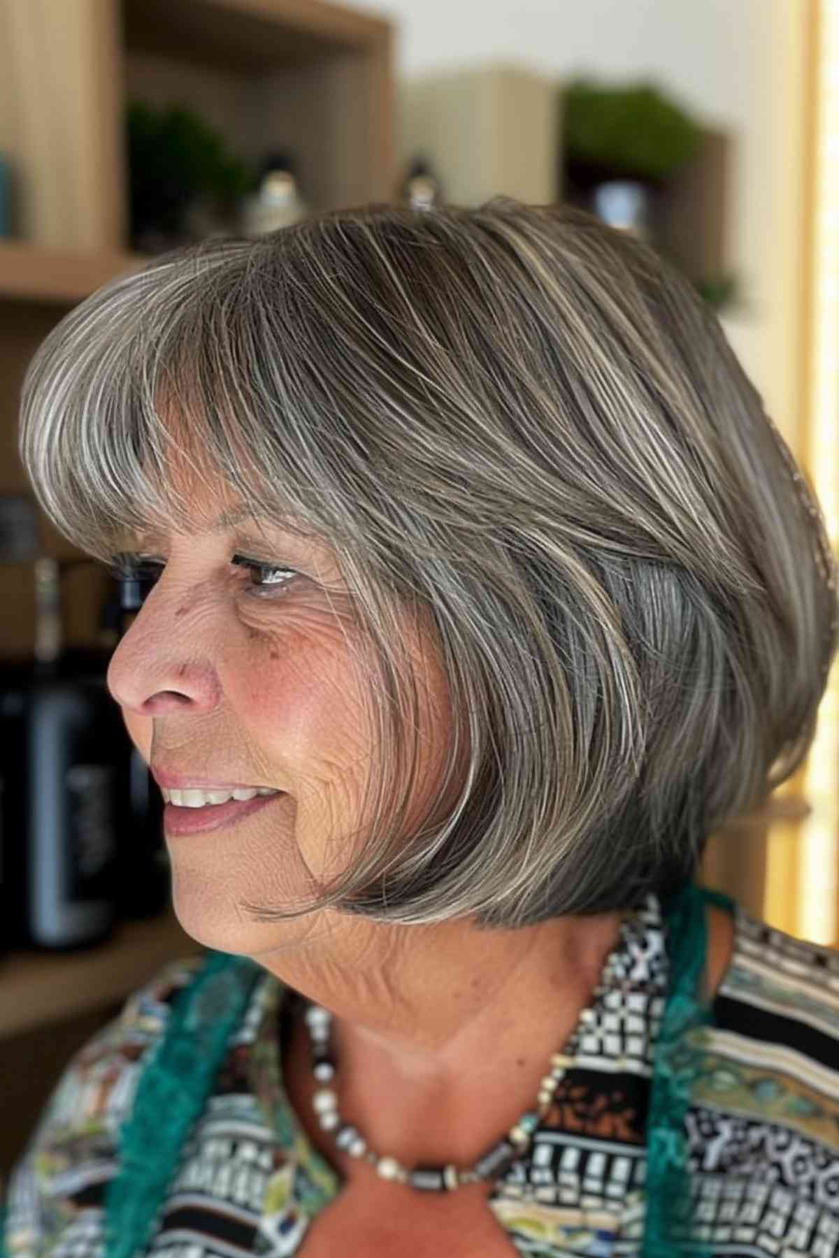 Sophisticated mature woman with glamorous grey hair and chic bangs that complement her natural elegance.