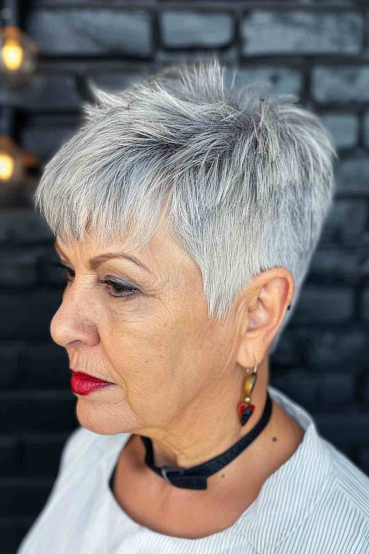Mature woman sporting a silver pixie cut with edgy bangs and textured layers for a modern look.