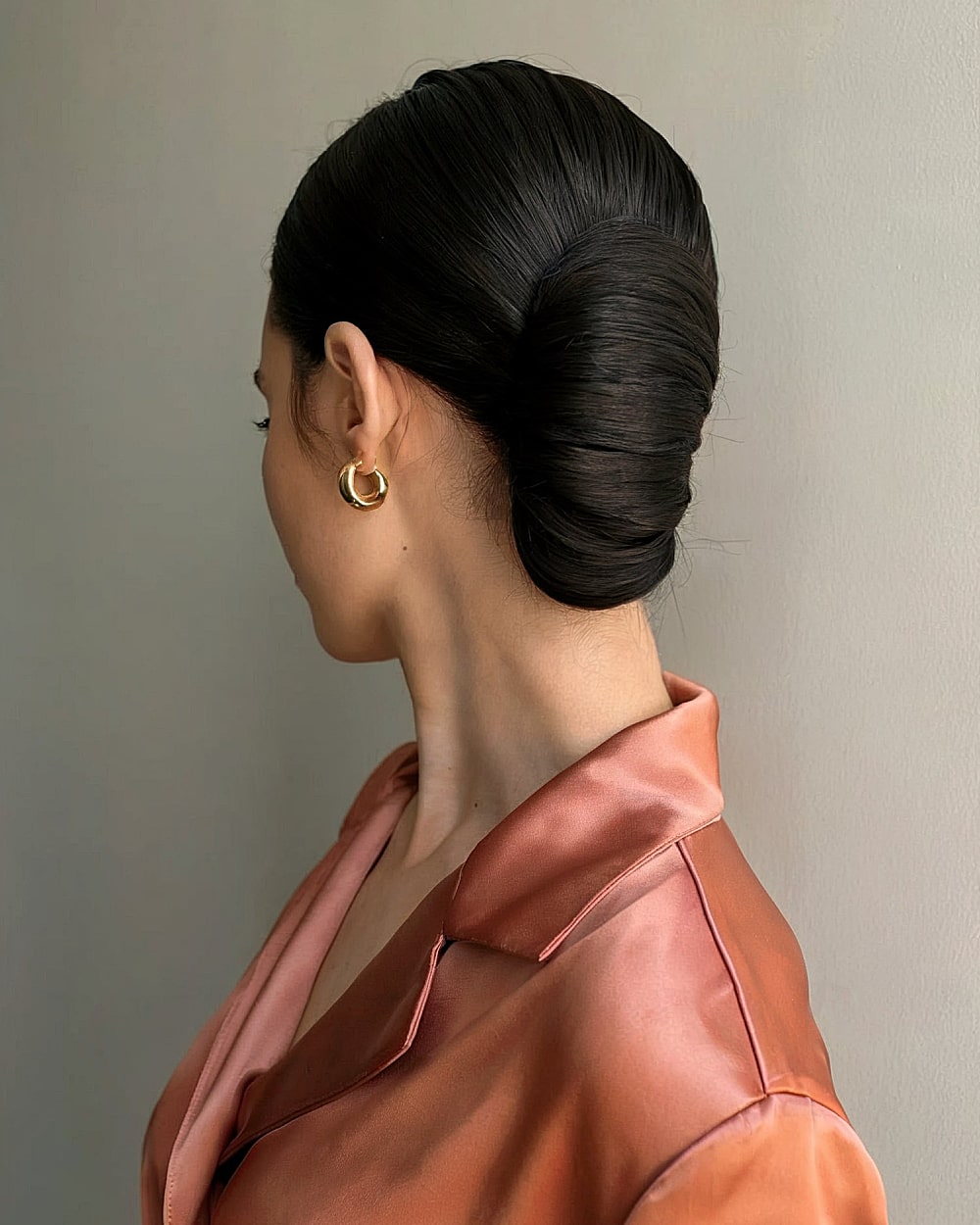 Sleek classic French roll updo with smooth polished finish for thick straight hair