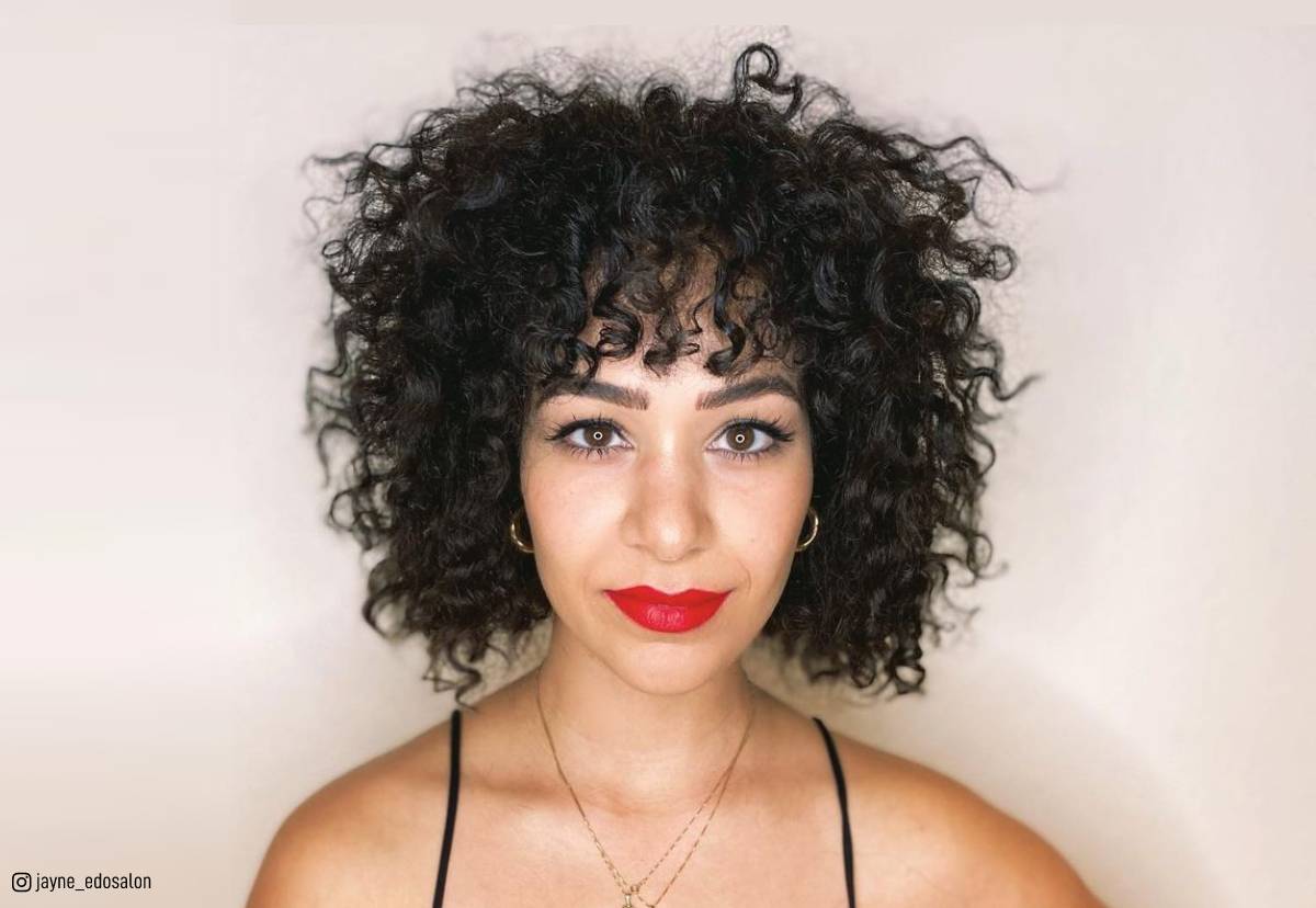 Image of Woman with red curly hair angled blunt bangs