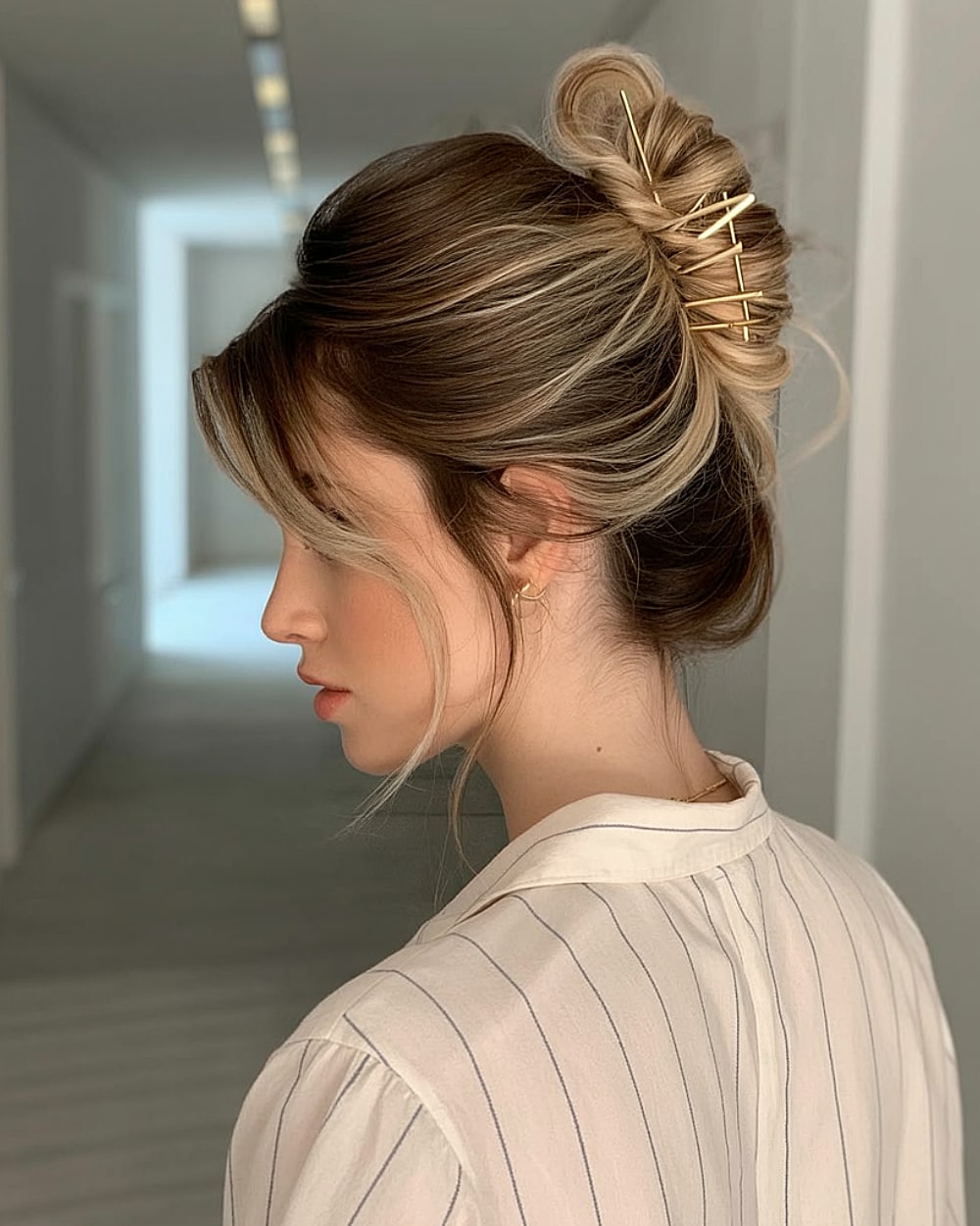 Twisted French updo with decorative gold pins and curtain bangs