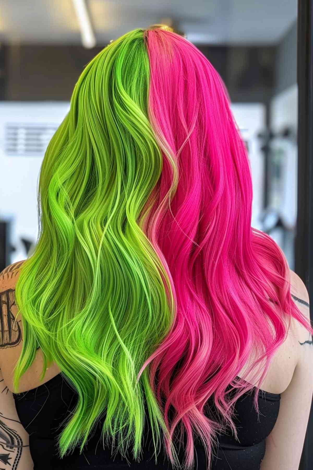 Split-dyed hair in bright green and pink, straight, mid-back length, showcasing Gemini duality.