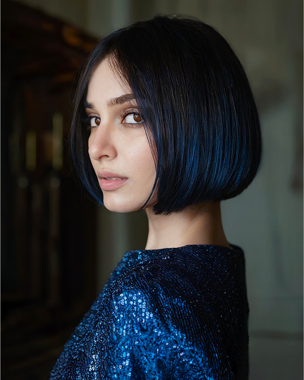 Glossy pinch bob with side-swept front and deep navy-black sheen on sleek fine hair