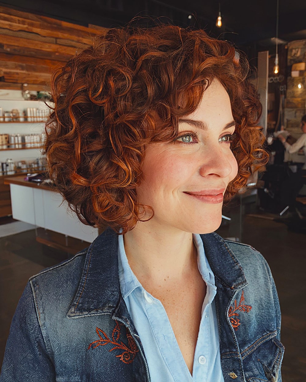 Layered stacked curly bob with copper tones and soft, round shape for thick curly hair