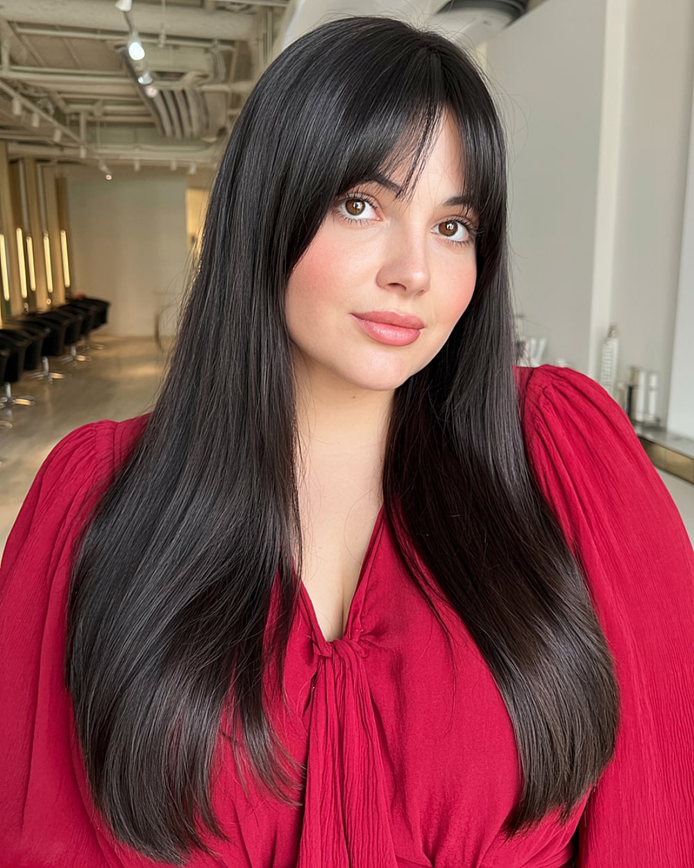 Glossy black long layers with curtain bangs enhancing round face structure