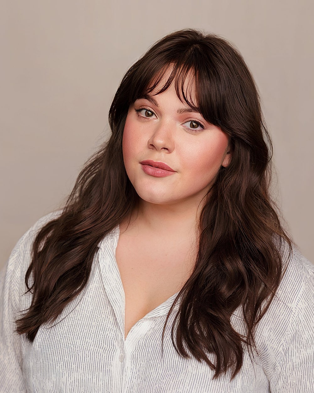 Long flowing brunette hair with short curtain bangs for round face contrast