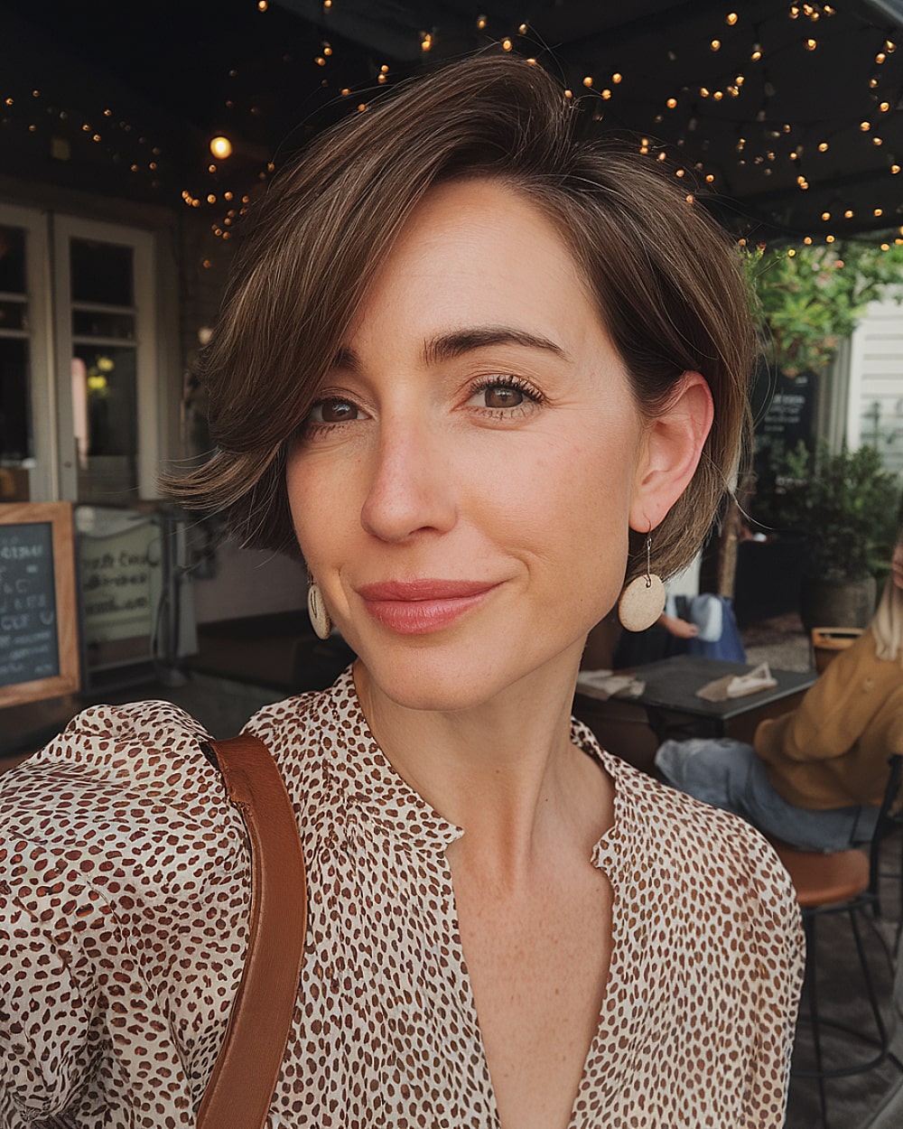 Long pixie bob with deep side part and smooth brown layers for women over 40