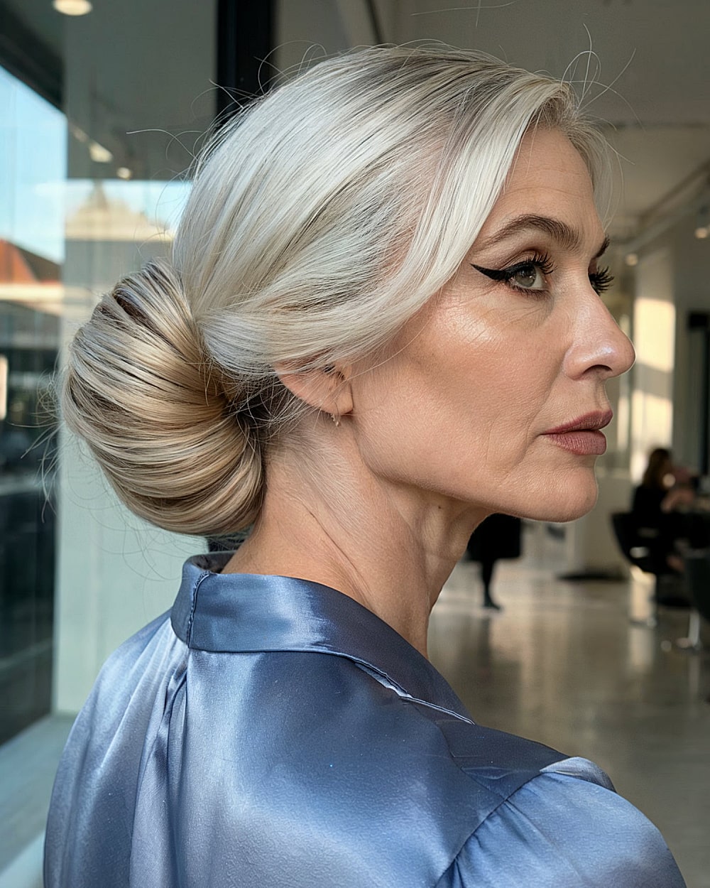 Smooth sculpted French twist bun for formal evening with platinum blonde hair