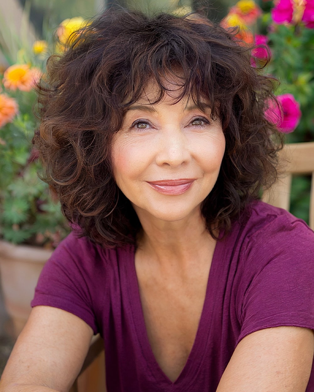 Layered shaggy haircut with volume and bangs to flatter round face shapes over 50