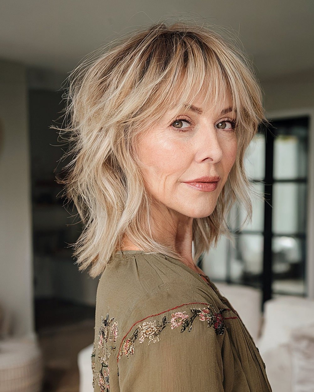 Chin-length shag haircut with bangs and choppy layers for textured volume on mature women