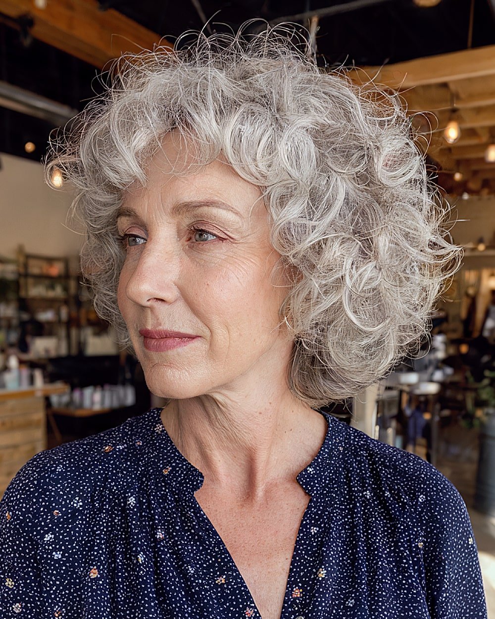 Shaggy stacked curly bob with wispy layers and tousled silver curls for mature hair