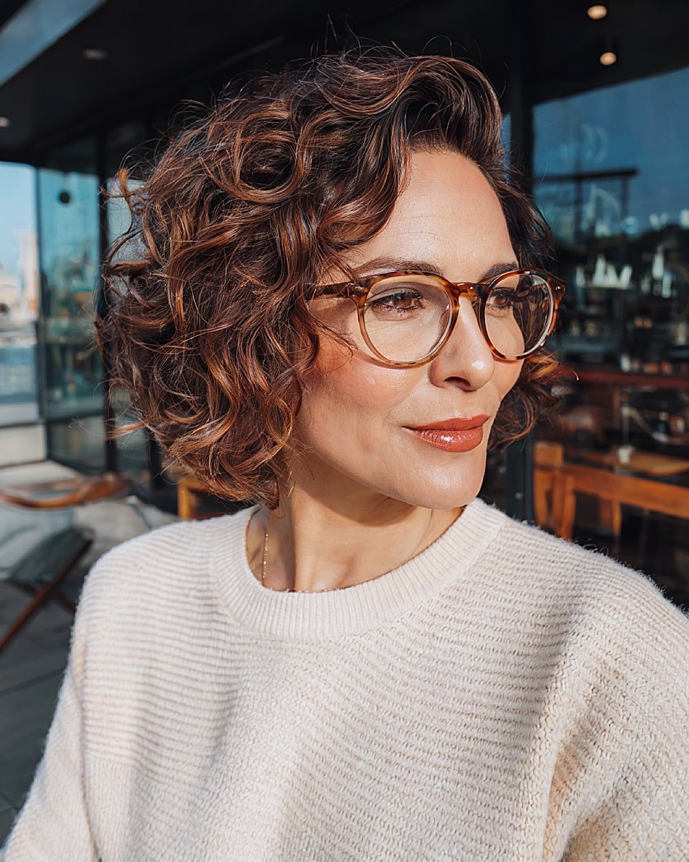 Stacked curly bob for oval face with tousled layers and soft side part