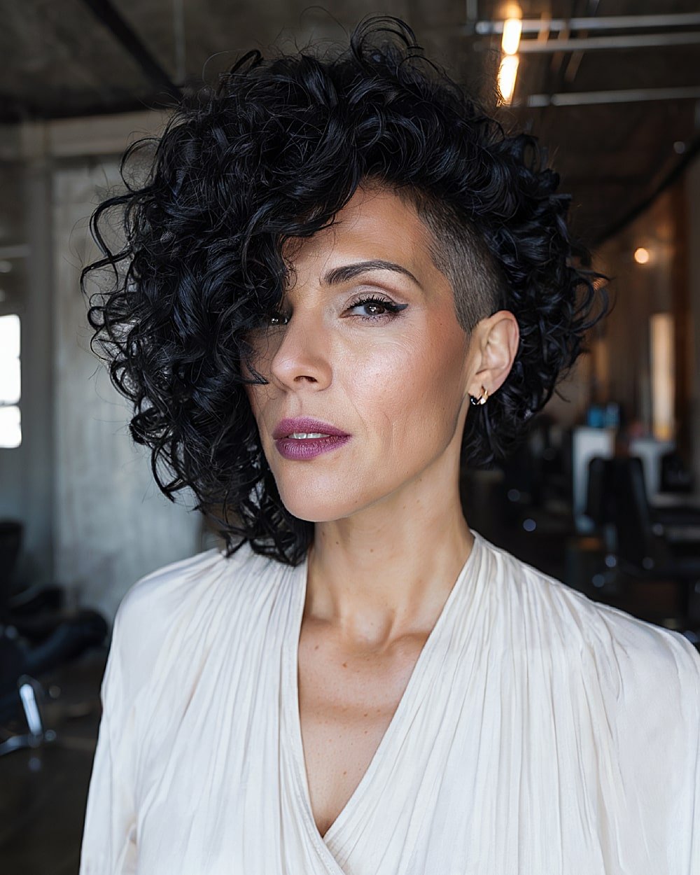 Undercut stacked curly bob with dramatic side sweep and shaved detail